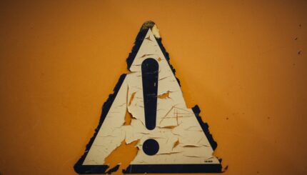 a triangle shaped sign on a yellow wall